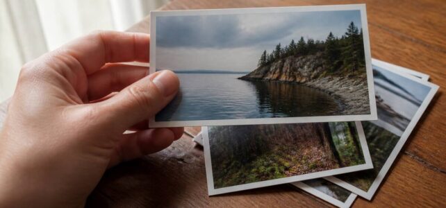 Hand die een fotoprint kiest met mat en glanzende papierlook onder zacht daglicht